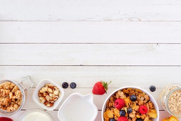 Cereal and ingredients for a healthy breakfast forming a bottom border over a white wood background. Top view. Copy space.