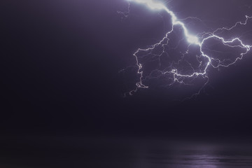 Wall Mural - lightning bolts reflection over the sea. taken during a thunderstorm over the ocean with clouds in the background