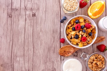 Wall Mural - cereal and ingredients for a healthy breakfast forming a side border over a wood background. top vie