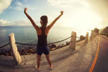 Girl with arms outstretched at a seaside. Beautiful inspiring landscape and sea with girl and hands raised on sunrise..