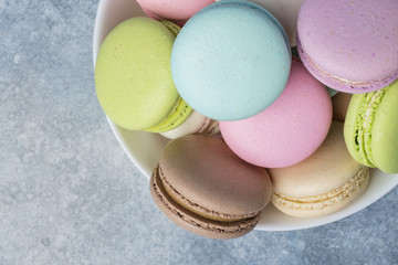 Colorful makarons in a white plate on a blue background. Copy space 2