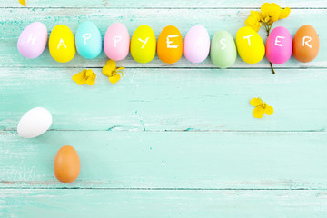 Wall Mural - Colorful Easter eggs with flower on rustic wooden planks background in blue paint. Holiday in spring season. vintage pastel color tone. top view composition.