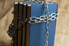 Books In Blue Binding Are Covered With A Chain Of Metal, A Chain In The Form Of A Cross