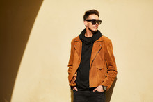 Model Looking Man Stand Near The Wall And Hold His Glasses Towards The Sun Shine