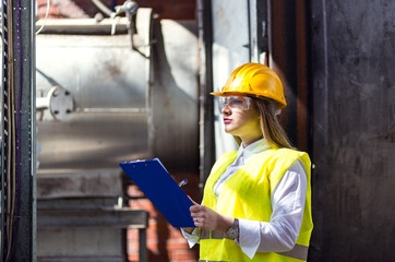 Young female engineer using clipboard.Female quality inspector at factory