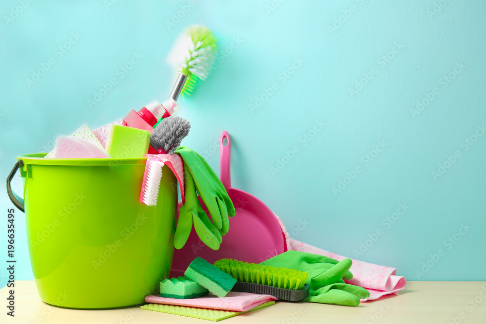Set of cleaning supplies on table against color background