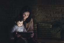 Mother And Daughter Using Digital Tablet At Home In The Dark