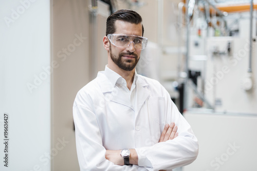 Portrait of man wearing lab coat and safety goggles in ...