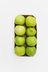 Eight fresh, ripe green yellow Golden Delicious or Granny smith apples neatly packed in spuermarket carboard box packaging one lying upside down, all others sideways