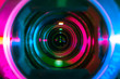 Video camera lens lit by pink or purple and blue neon light