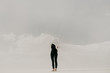 © Isaiah & Taylor Photography/Stocksy - Contrast of woman wearing black with white fabric hiding her face in the minimal landscape