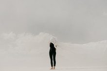 Contrast Of Woman Wearing Black With White Fabric Hiding Her Face In The Minimal Landscape