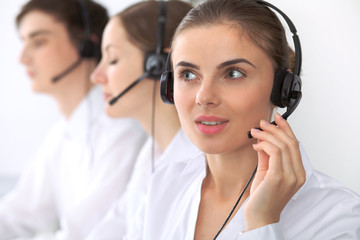 Wall Mural - Call center. Focus on beautiful woman in headset