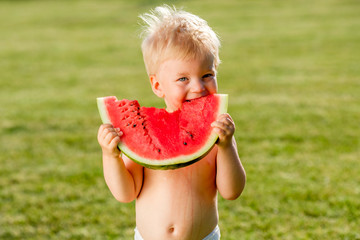 Wall Mural - One year old baby boy eating watermelon in the garden