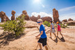 © Brocreative - Happy family hiking together in the beautiful rock formations of Arches National Park. Walking along a scenic trail with large rock unique formations in the background
