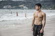 © theartofphoto - Half body shot of a handsome young man standing on a beach in Phuket Island, Thailand, shirtless wearing boxer shorts, showing muscular fit body