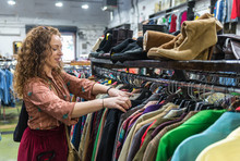 Woman Browsing Through Vintage Clothing In A Thrift Store.