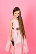 Girl child brush hair in fashionable dress on pink.