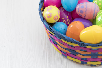  Easter eggs in basket on white wooden background
