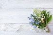 Bouquet of spring flowers lilies of the valley, forget me nots and daisies on a wooden background