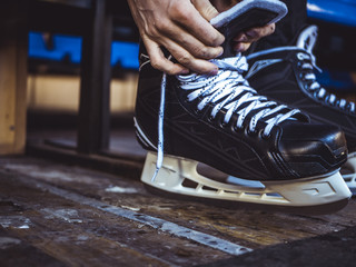 Wall Mural - close up shot of hand tie shoelaces of ice hockey skates in locker room