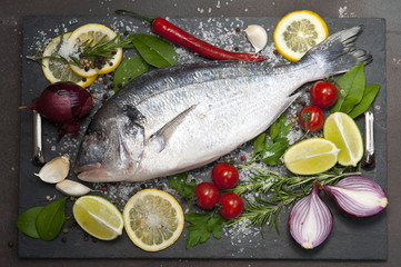 Fresh Dorado fish with spices and vegetables on slate plate