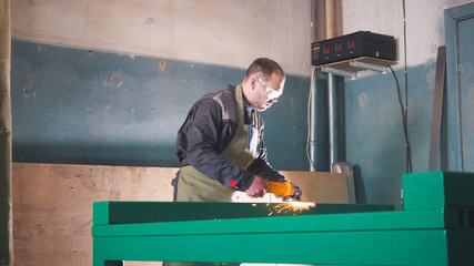 The worker male grinding the steel mechanism on industry