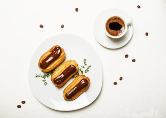 Wall Mural - Eclairs cakes and morning espresso coffee in a cup, unhealthy breakfast, white background, top view