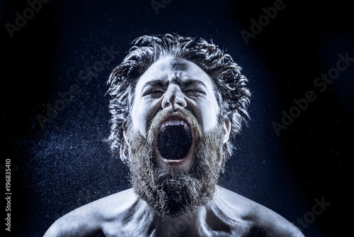 Cuadros en Lienzo A bearded man angrily screams into a spray of water against a black background