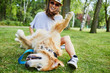 © baranq - Joyful young woman playing with her dog outdoors in the park