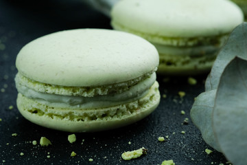 Tasty sweet green macarons cakes on dark background, dark mood