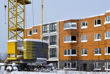 Abandoned construction of a multi-storey building. Tower crane, and a house with broken glass. Winter. Russia