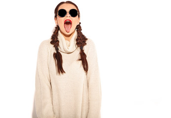 Young happy smiling woman model with bright makeup and red lips with two horns  in summer warm sweater clothes isolated on white. Going crazy and showing her tongue