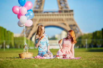 Wall Mural - Two young women having picnic near the Eiffel tower in Paris, France