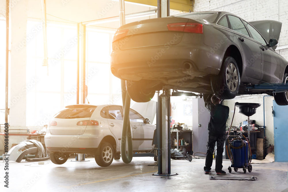 Car service center. Vehicle raised on lift at maintenance station. Auomobile repair and check up
