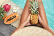 © WHstudio Leushin N - Suntanned female has slender legs, holds exotic pineapple, spends vacation in luxurious hotel, sits near pool with blue water, surrounded with tropical fruits. Summer time and recreation concept