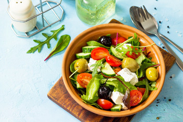 Wall Mural - Greek salad with fresh vegetables, feta cheese and black olives on a blue stone or concrete table. Diet, concept of vegetarian food. Copy space.