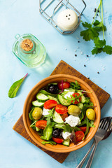 Wall Mural - Greek salad with fresh vegetables, feta cheese and black olives on a blue stone or concrete table. Diet, concept of vegetarian food. Copy space, top view flat lay background.