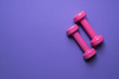 © tatomm - two pink dumbbell on purple background, sport and healthy concept