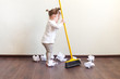 child sweeps broom with paper bins in the apartment, household chores