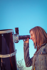 Wall Mural - cute young woman holding astronomical telescope and looking at the sky.