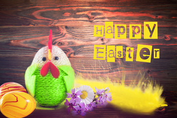 Happy Easter. Colorful easter chick, eggs and yellow feather on wooden background. greeting card