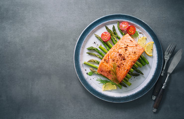 Grilled salmon garnished with green asparagus and tomatoes