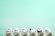 Eggs with funny faces in carton package on mint background