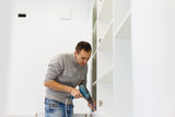 Fototapeta Łazienka - Carpenter screwing solid maple cabinets into the wall white spot in drill