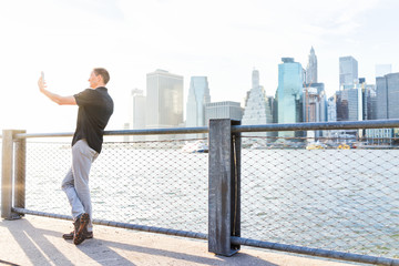 Wall Mural - Back of young man outside outdoors in NYC New York City Brooklyn Bridge Park by east river, railing, looking at view of cityscape skyline