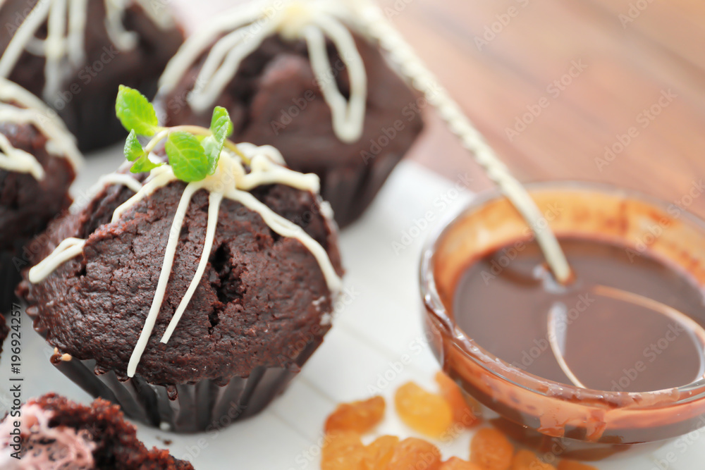 Wooden board with tasty chocolate cupcakes on table