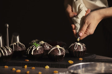 Canvas Print - Woman decorating tasty cupcake with frosting at table