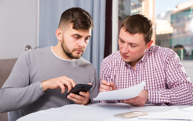 Wall Mural - Serious males with documents and phone at home table