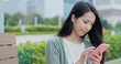 © leungchopan - Woman use of cellphone in city park